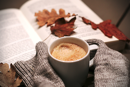 Pause rigenerative, tazza di caffelatte, foglie autunnali, libro aperto